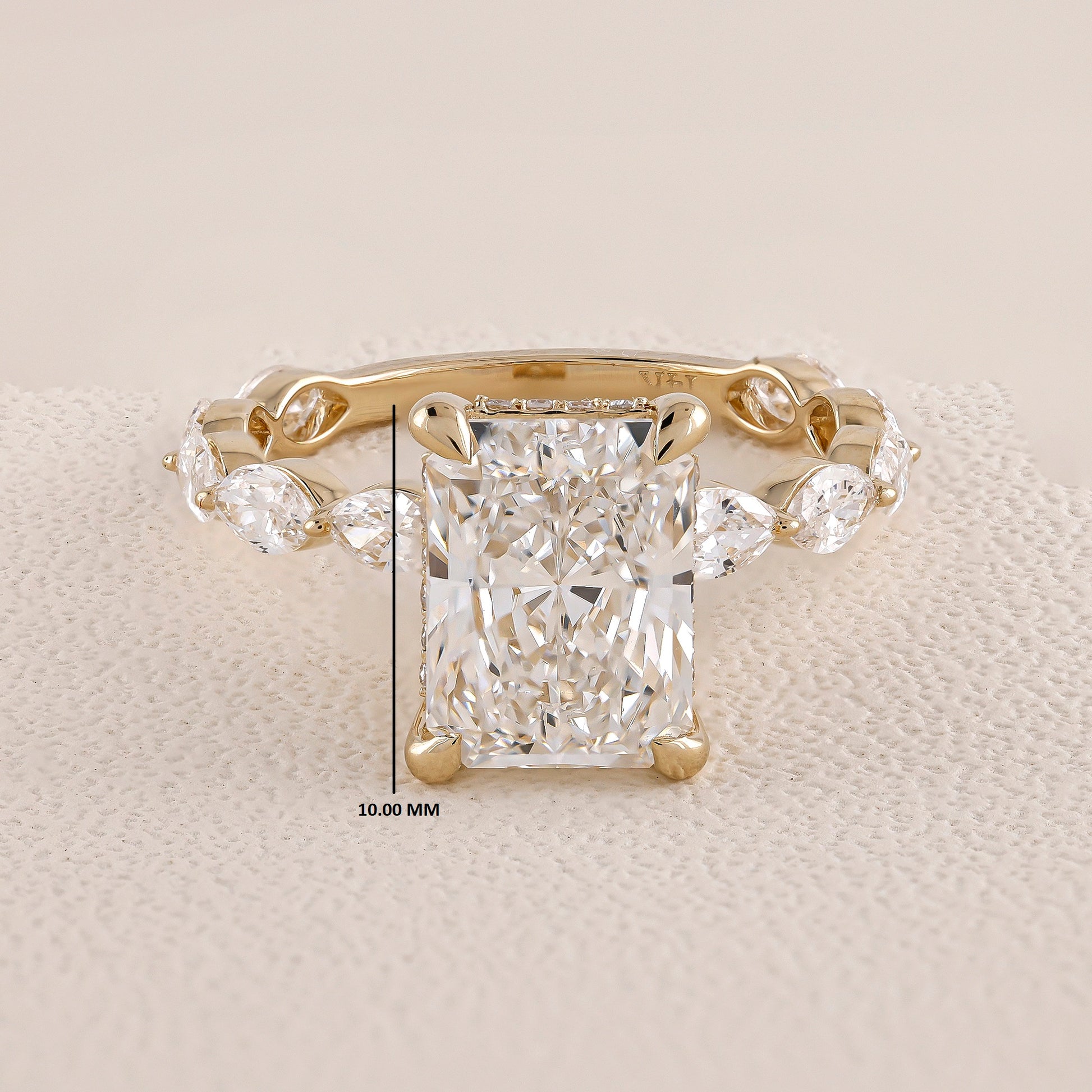 Gold ring with a large diamond and smaller side stones on a beige background