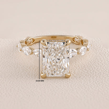 Gold ring with a large diamond and smaller side stones on a beige background