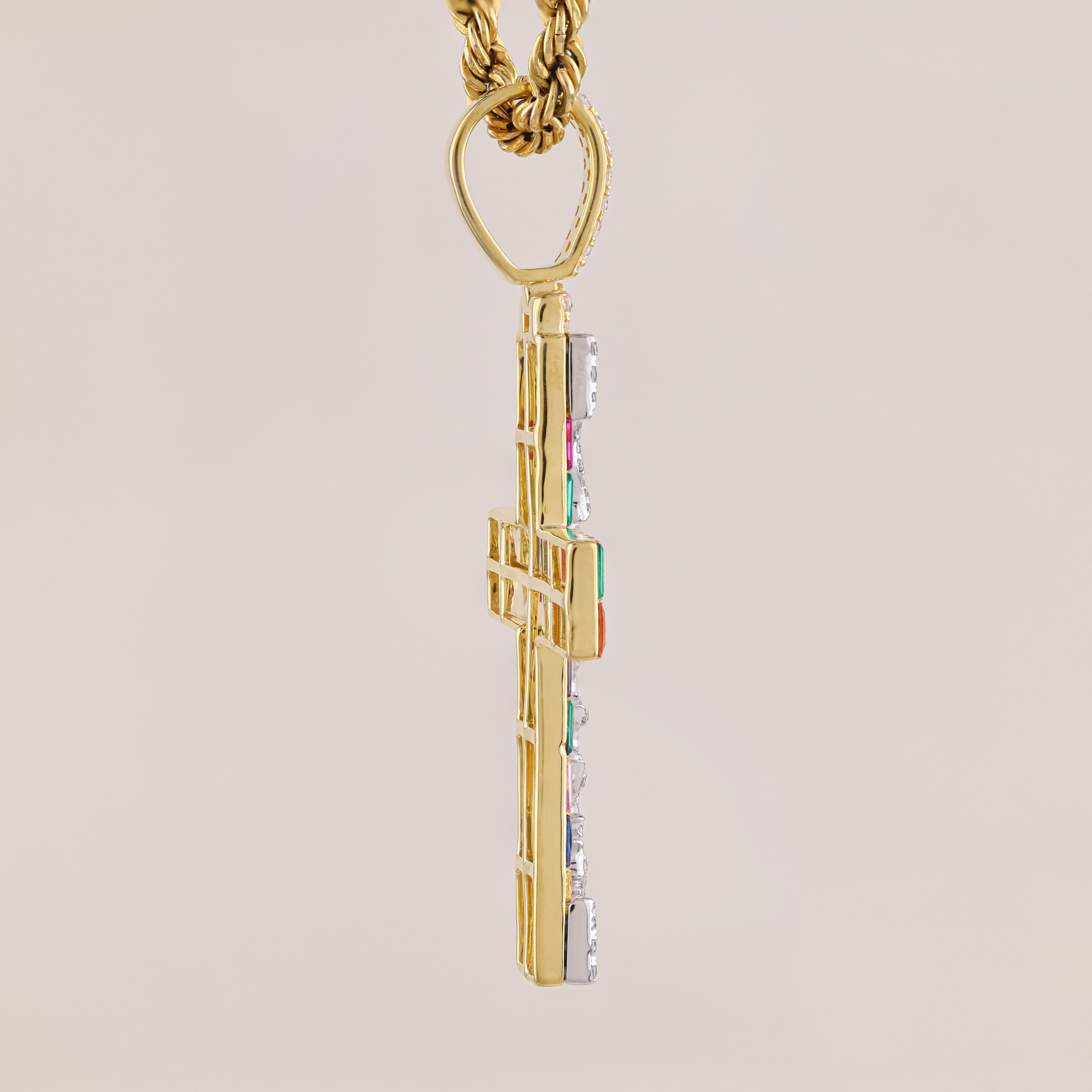 Gold cross pendant with colorful accents on a beige background