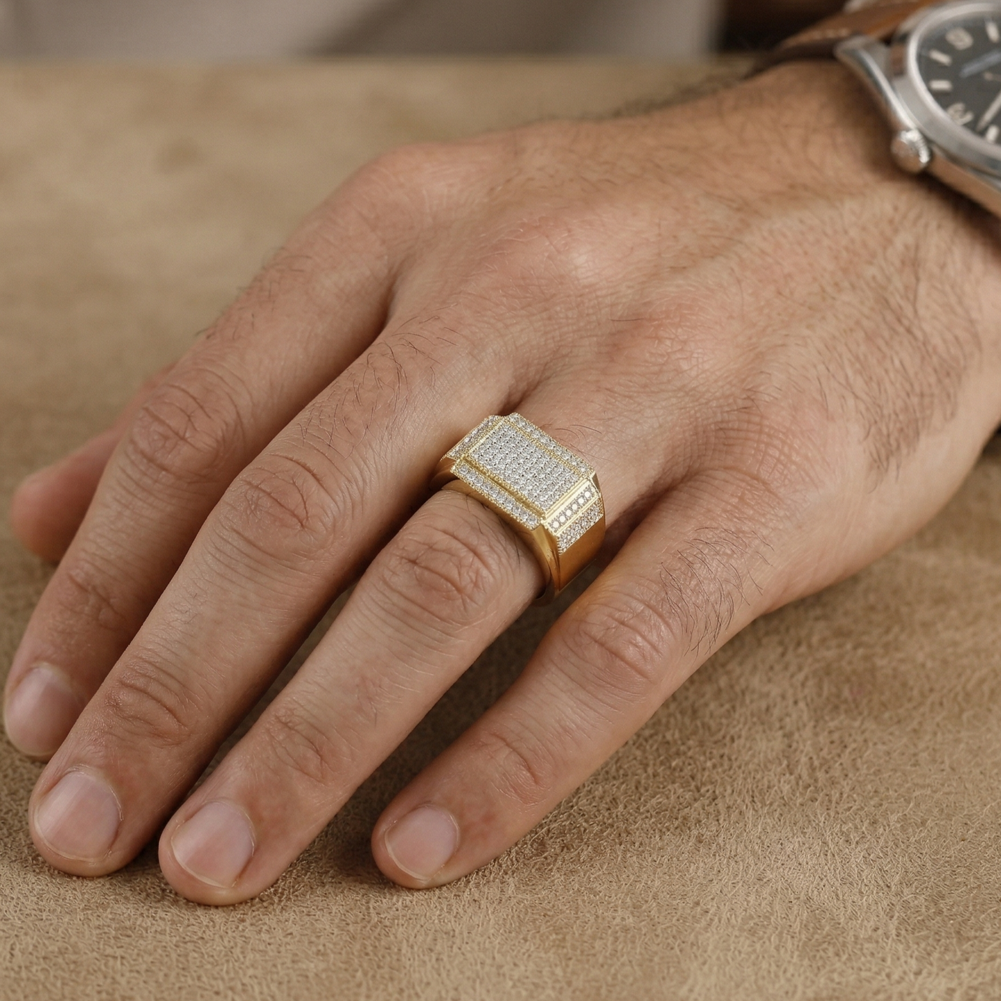 Gold ring with diamonds on a person's finger against a beige background