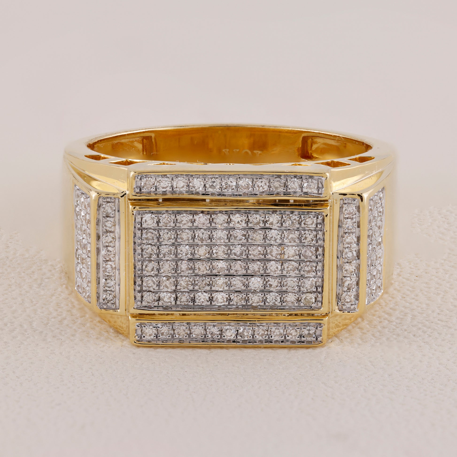 Gold ring with diamond accents on a light gray background