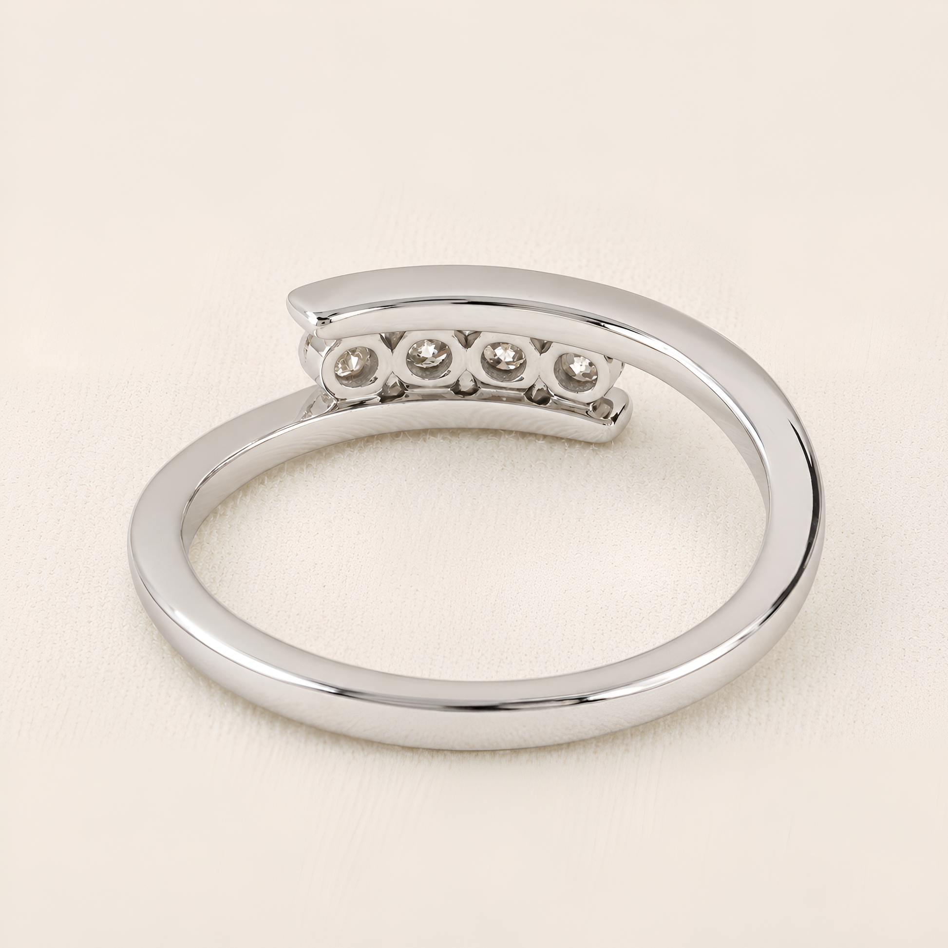 A polished silver-tone open ring band featuring a curved top section with five small round clear gemstones, photographed on a light cream background.