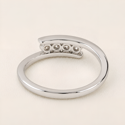 A polished silver-tone open ring band featuring a curved top section with five small round clear gemstones, photographed on a light cream background.