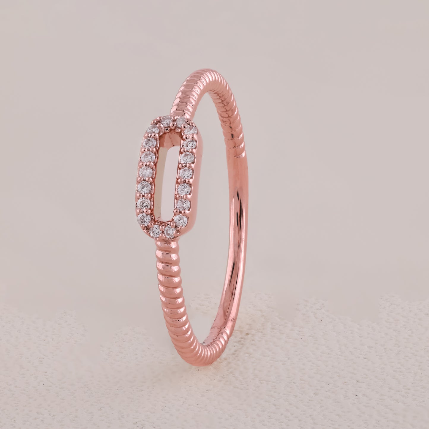 Rose gold ring with diamond accents on a light beige background