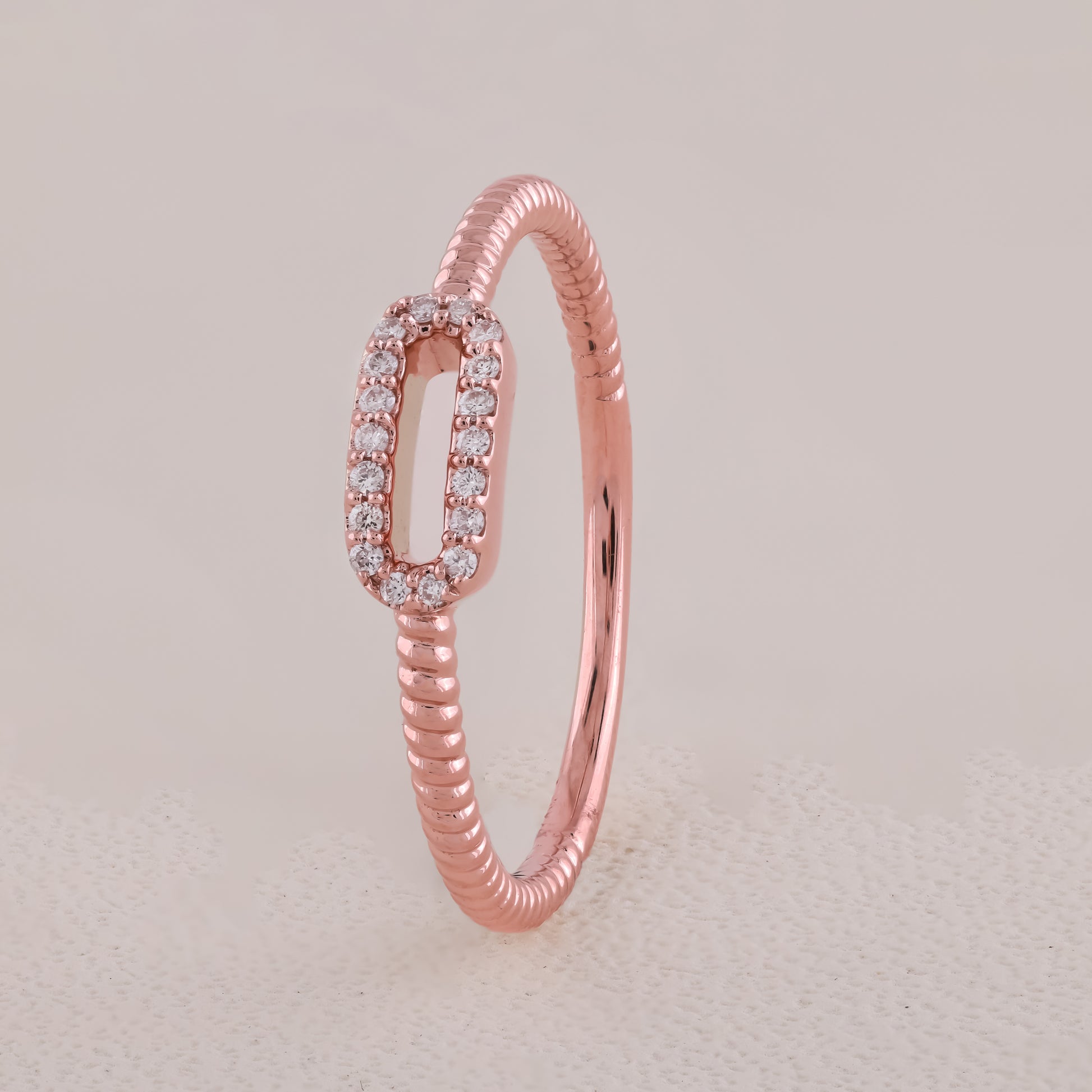 Rose gold ring with diamond accents on a light beige background