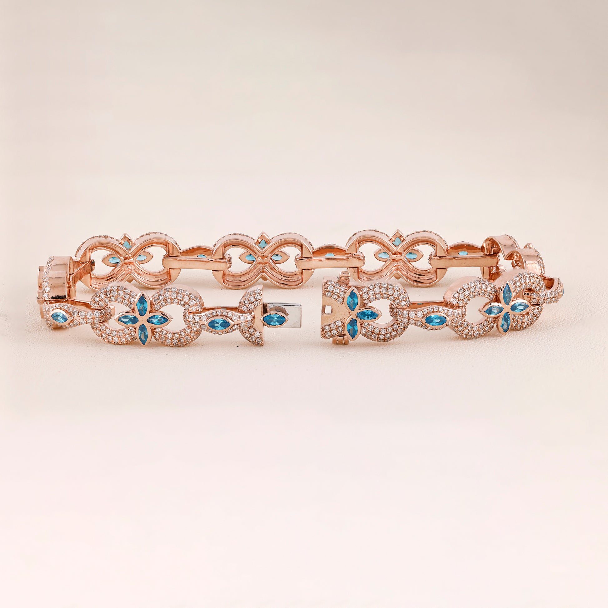 Rose gold bracelet with blue gemstones on a light beige background