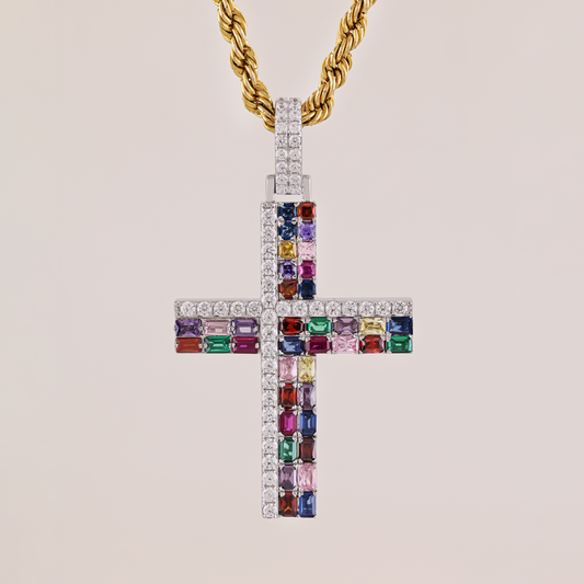 Cross-shaped pendant with colorful gemstones and a gold chain on a beige background