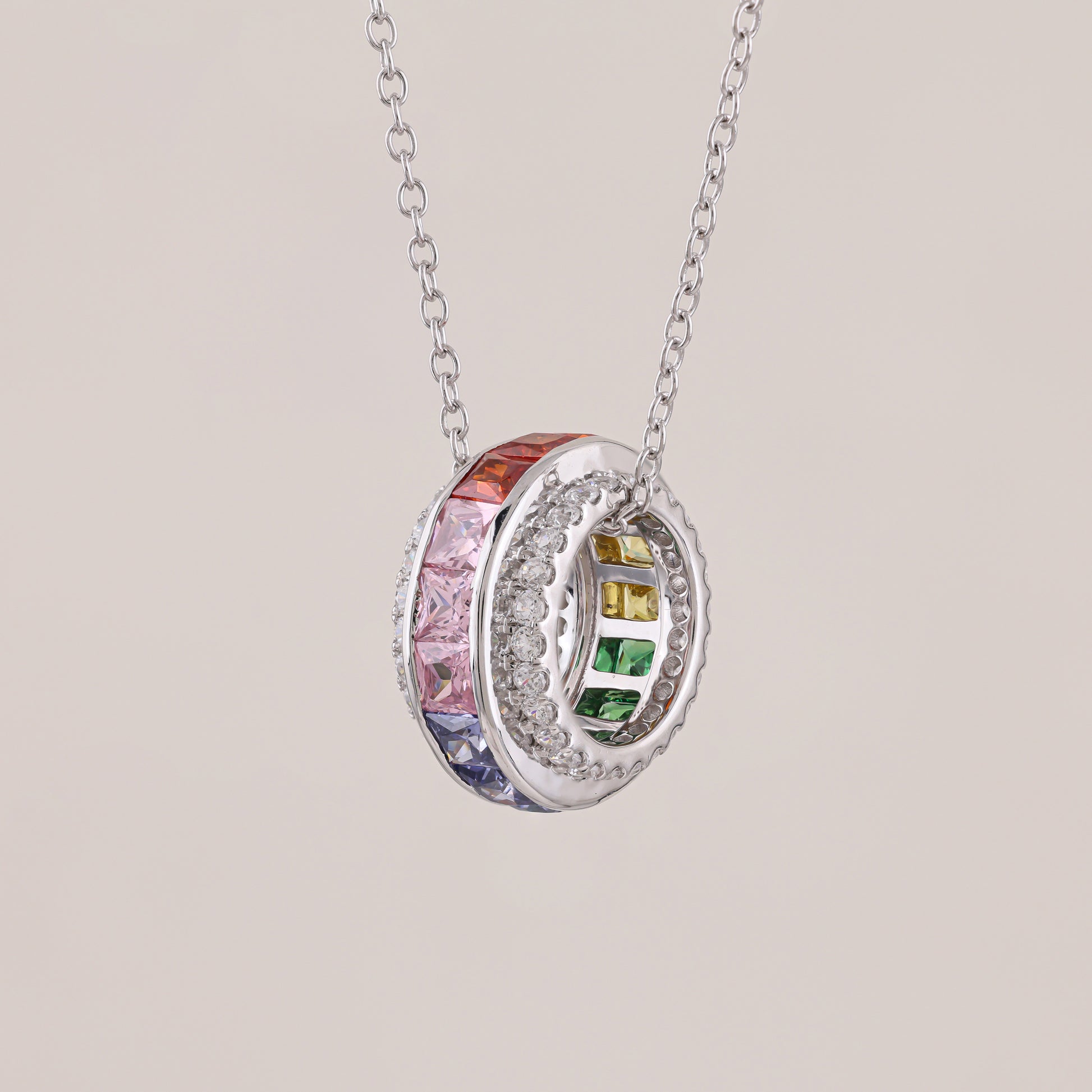 Silver necklace with a circular pendant featuring colorful gemstones on a light gray background