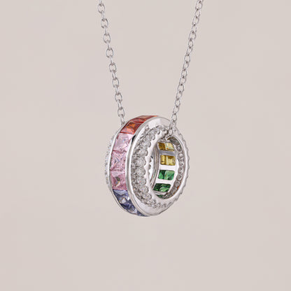Silver necklace with a circular pendant featuring colorful gemstones on a light gray background