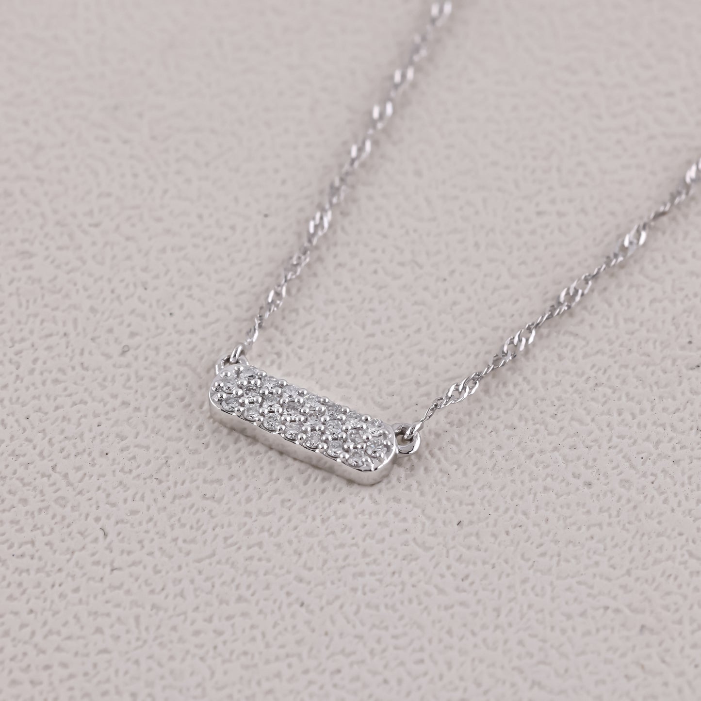 Silver necklace with a bar pendant on a light gray background
