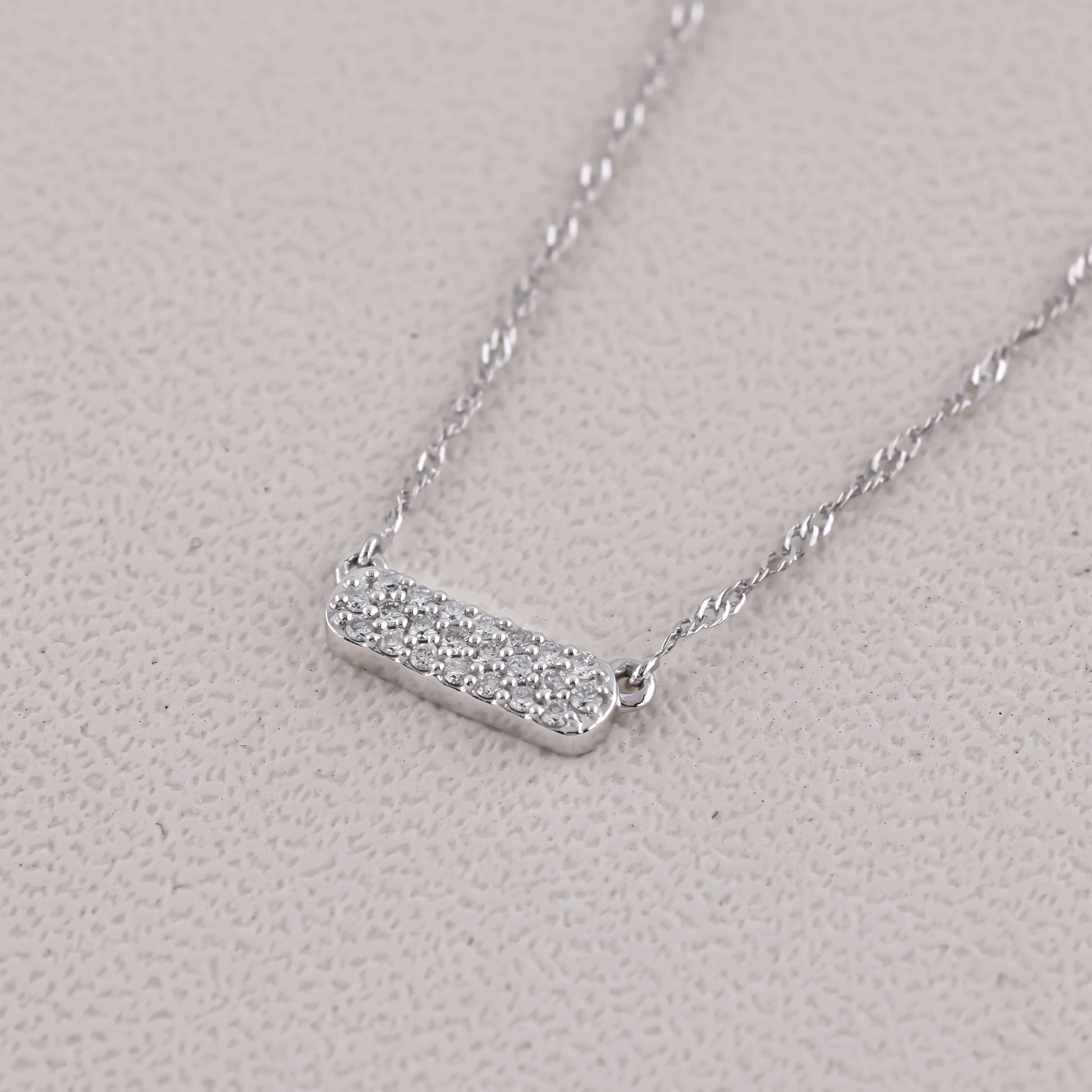 Silver necklace with a bar pendant on a light gray background