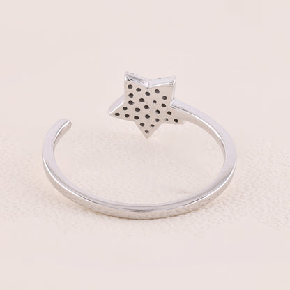 Silver ring with a star-shaped top on a beige background