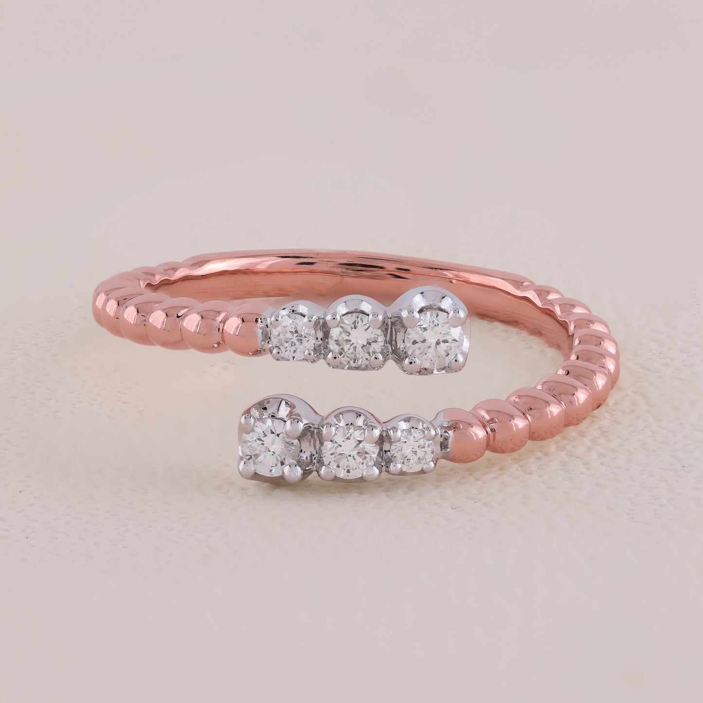 Rose gold ring with diamond accents on a light beige background