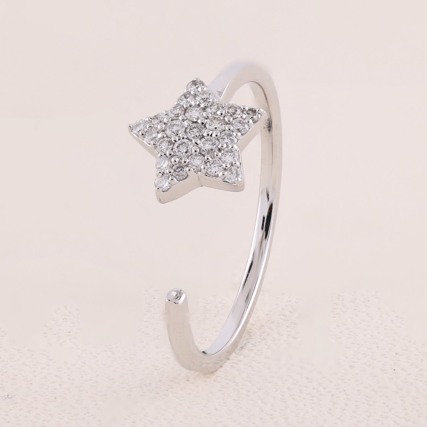 Silver star-shaped ring with embedded stones on a light beige background