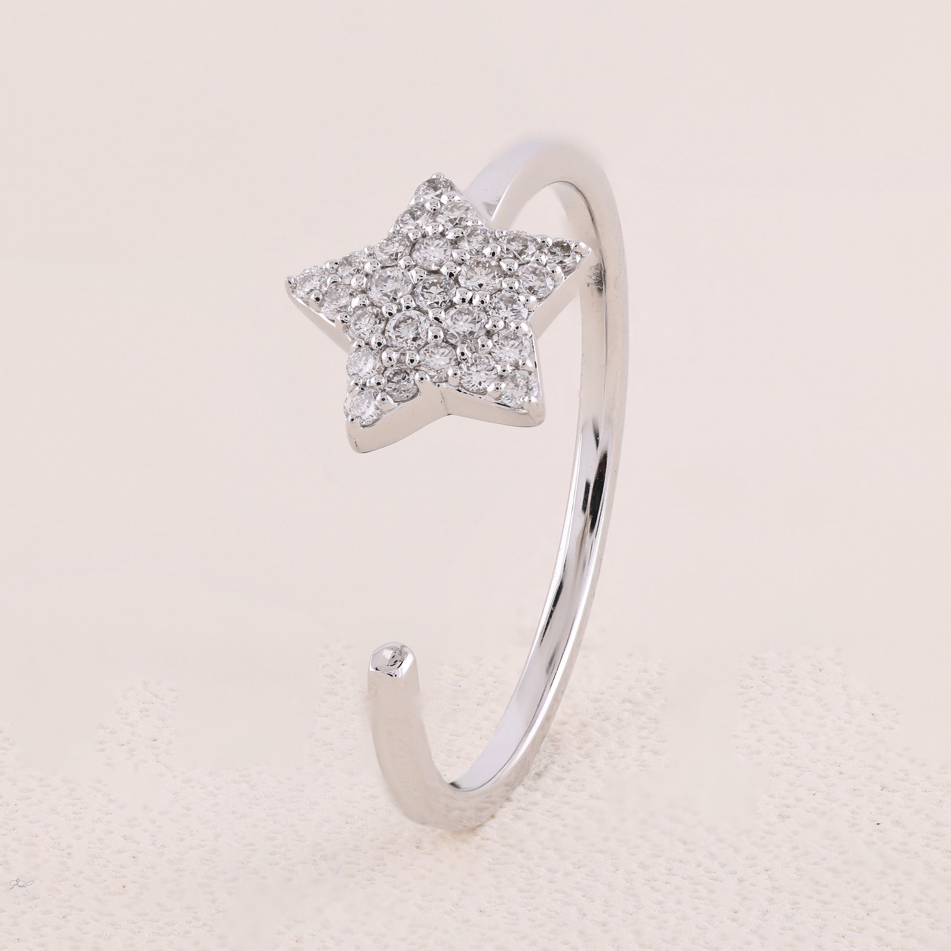 Silver star-shaped ring with embedded stones on a light beige background