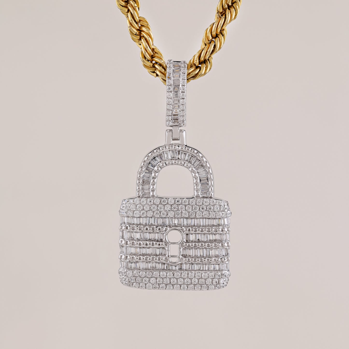 Diamond-encrusted lock-shaped pendant on a gold chain against a light gray background