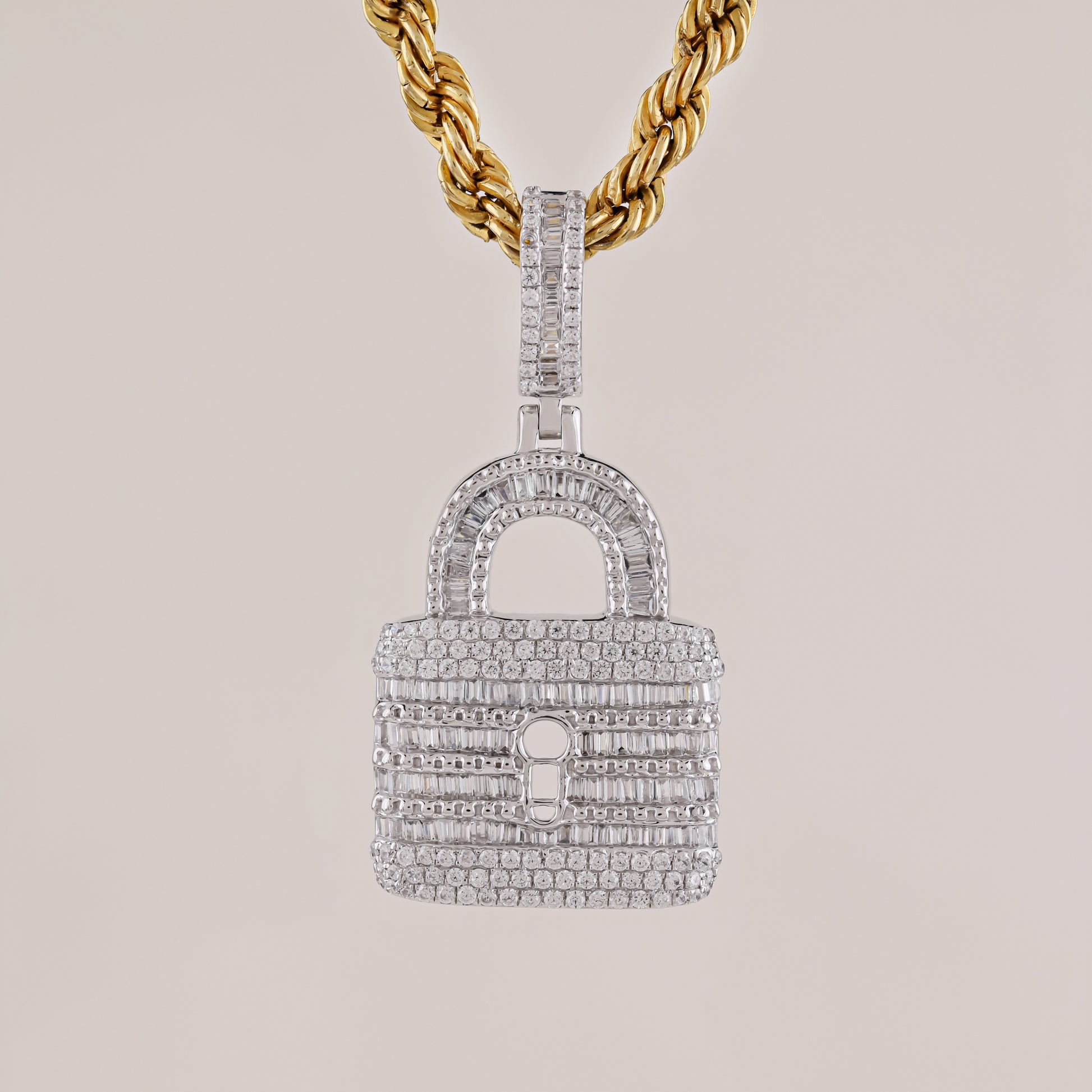 Diamond-encrusted lock-shaped pendant on a gold chain against a light gray background