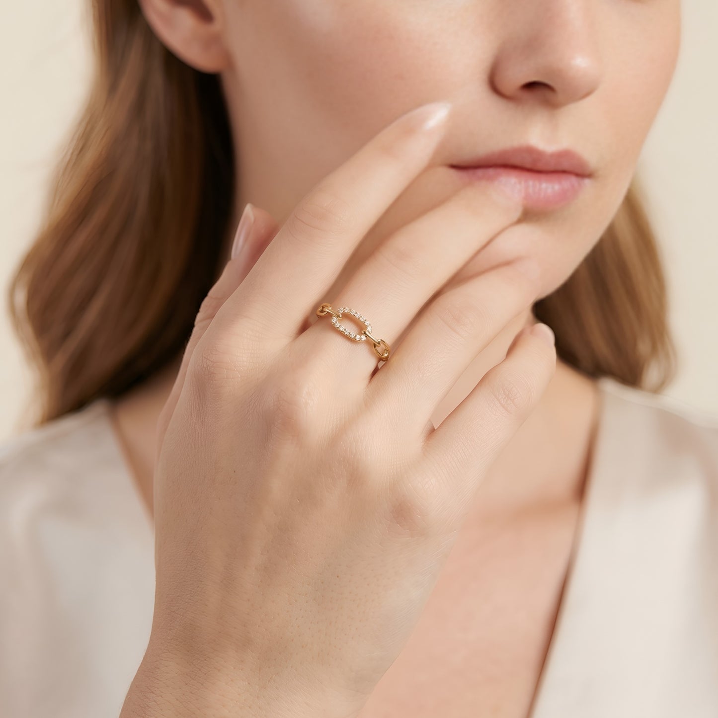 Close-up of a woman's hand wearing a gold ring with a beige background