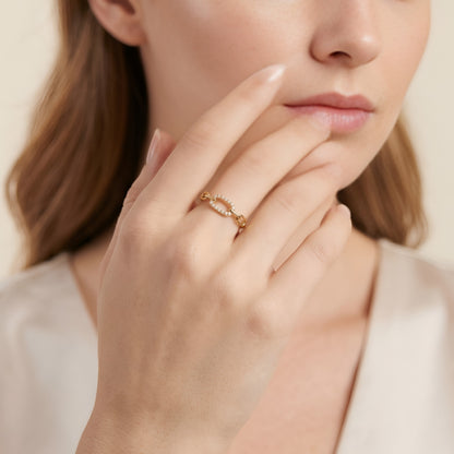 Close-up of a woman's hand wearing a gold ring with a beige background