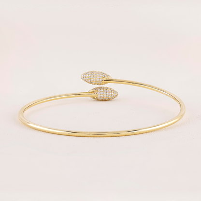 Gold bracelet with heart-shaped ends on a light pink background