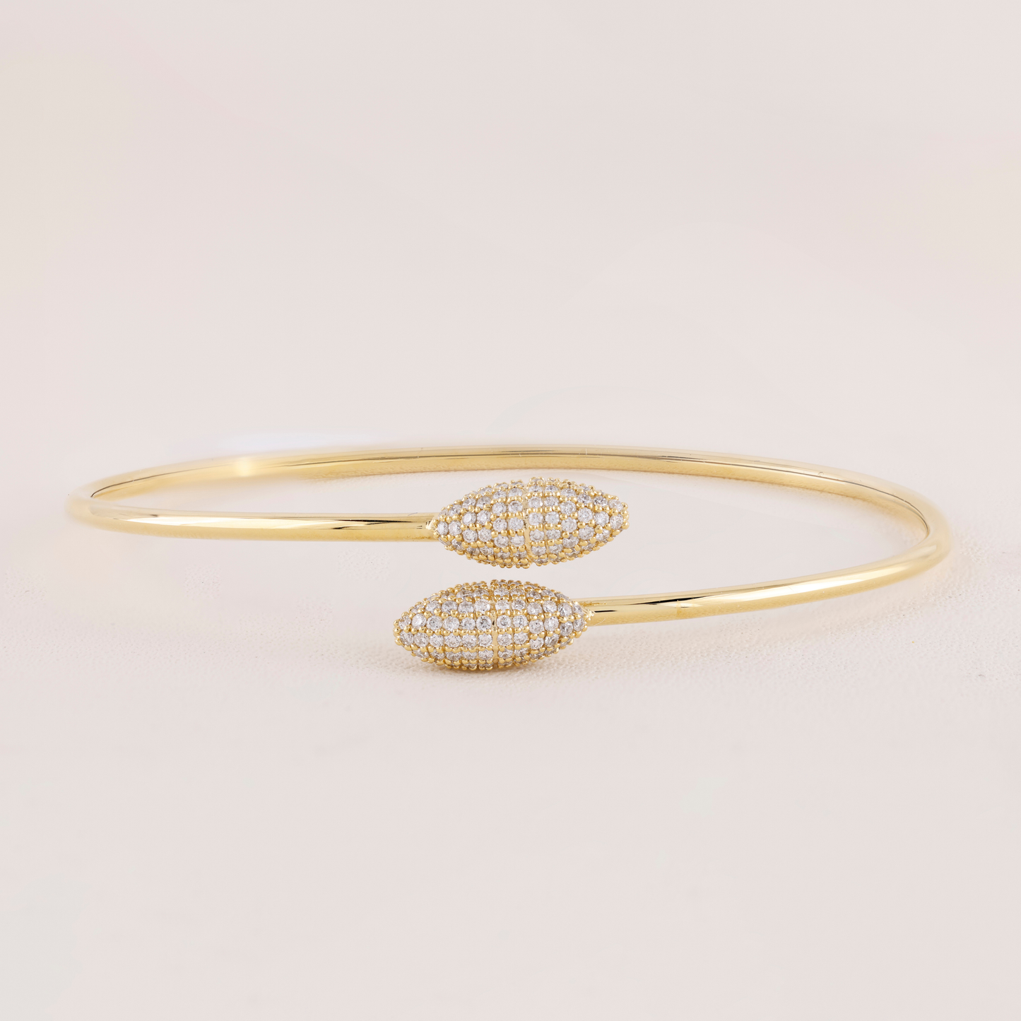 Gold bracelet with diamond accents on a light beige background