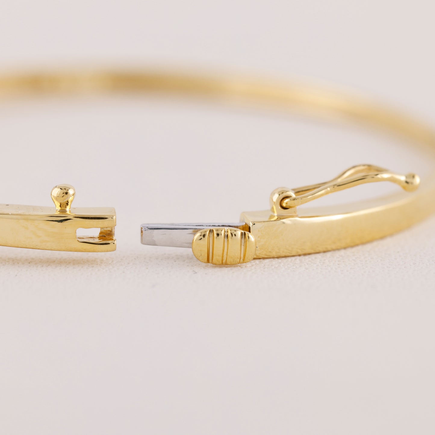 Gold bracelet with a clasp on a light beige background