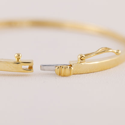 Gold bracelet with a clasp on a light beige background