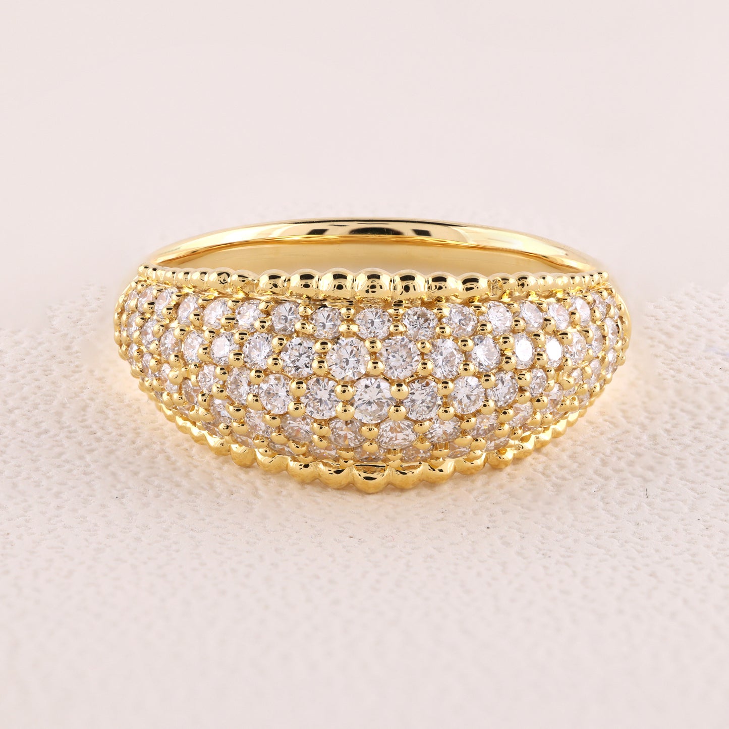 Gold ring with diamond accents on a light beige background