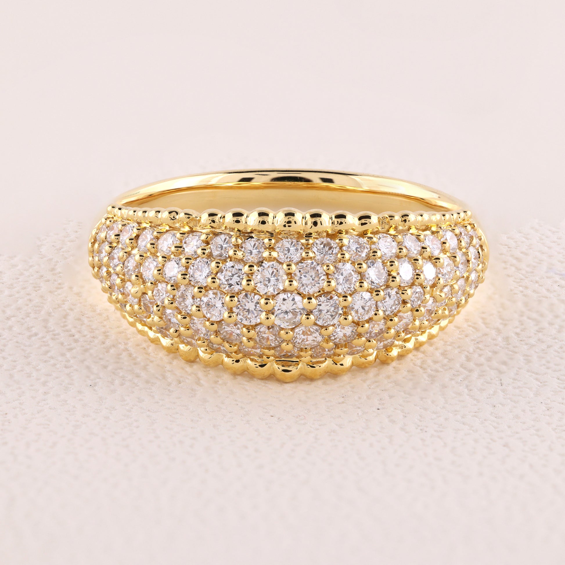 Gold ring with diamond accents on a light beige background