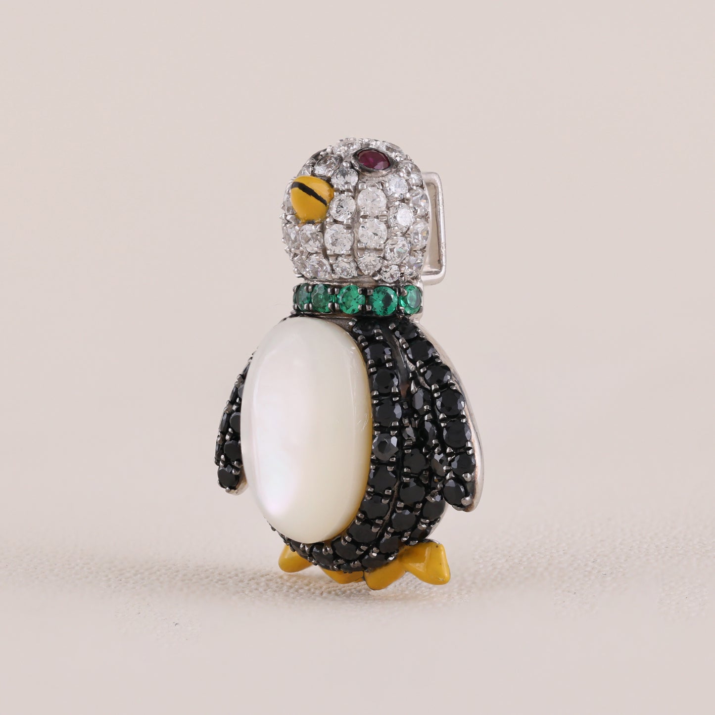 Jeweled penguin brooch on a beige background