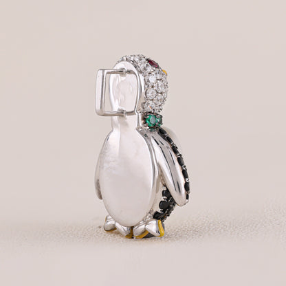 Penguin-shaped jewelry charm with gemstones on a beige background