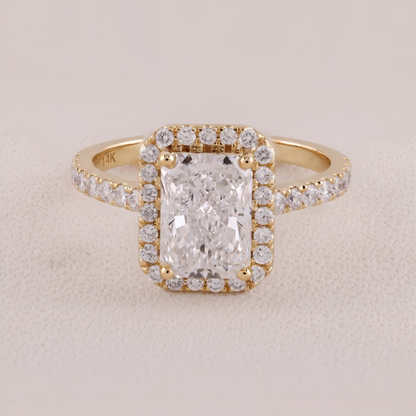 Gold ring with a large diamond and smaller diamonds on a beige background