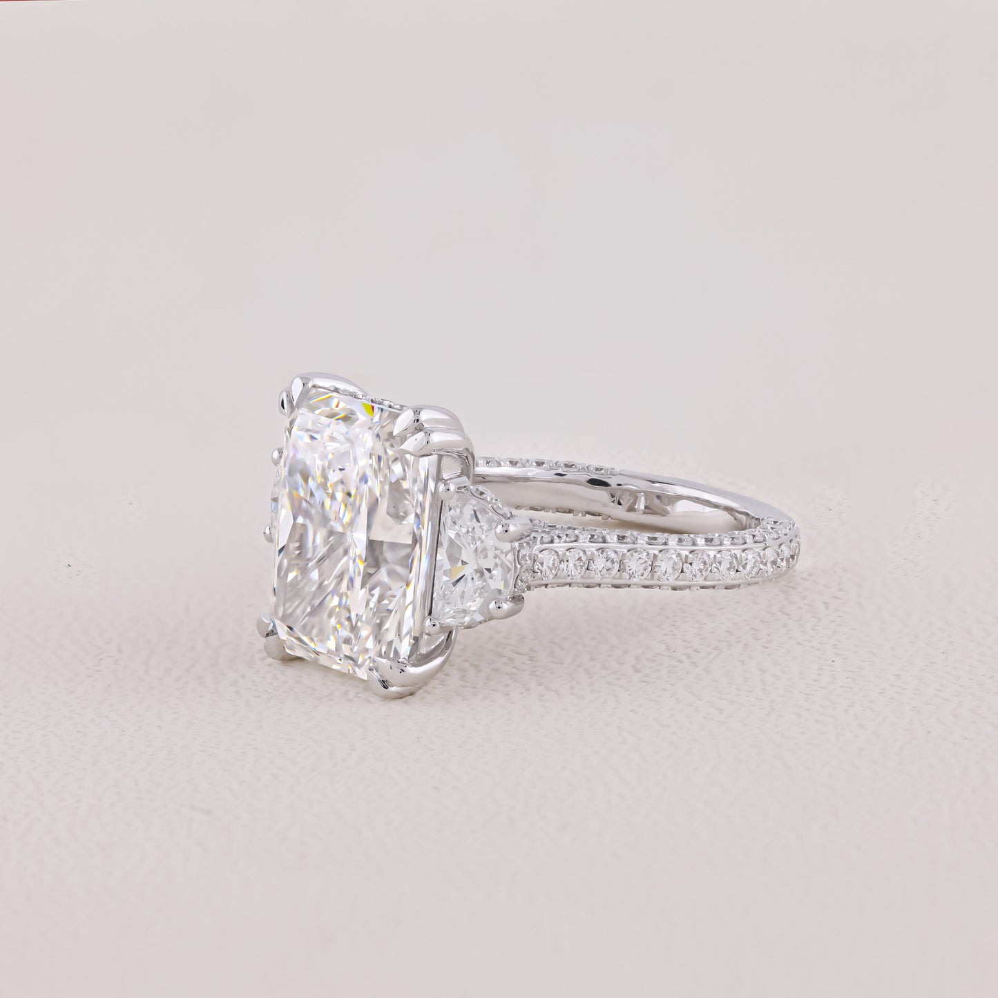 Diamond ring with a large central gemstone on a light gray background