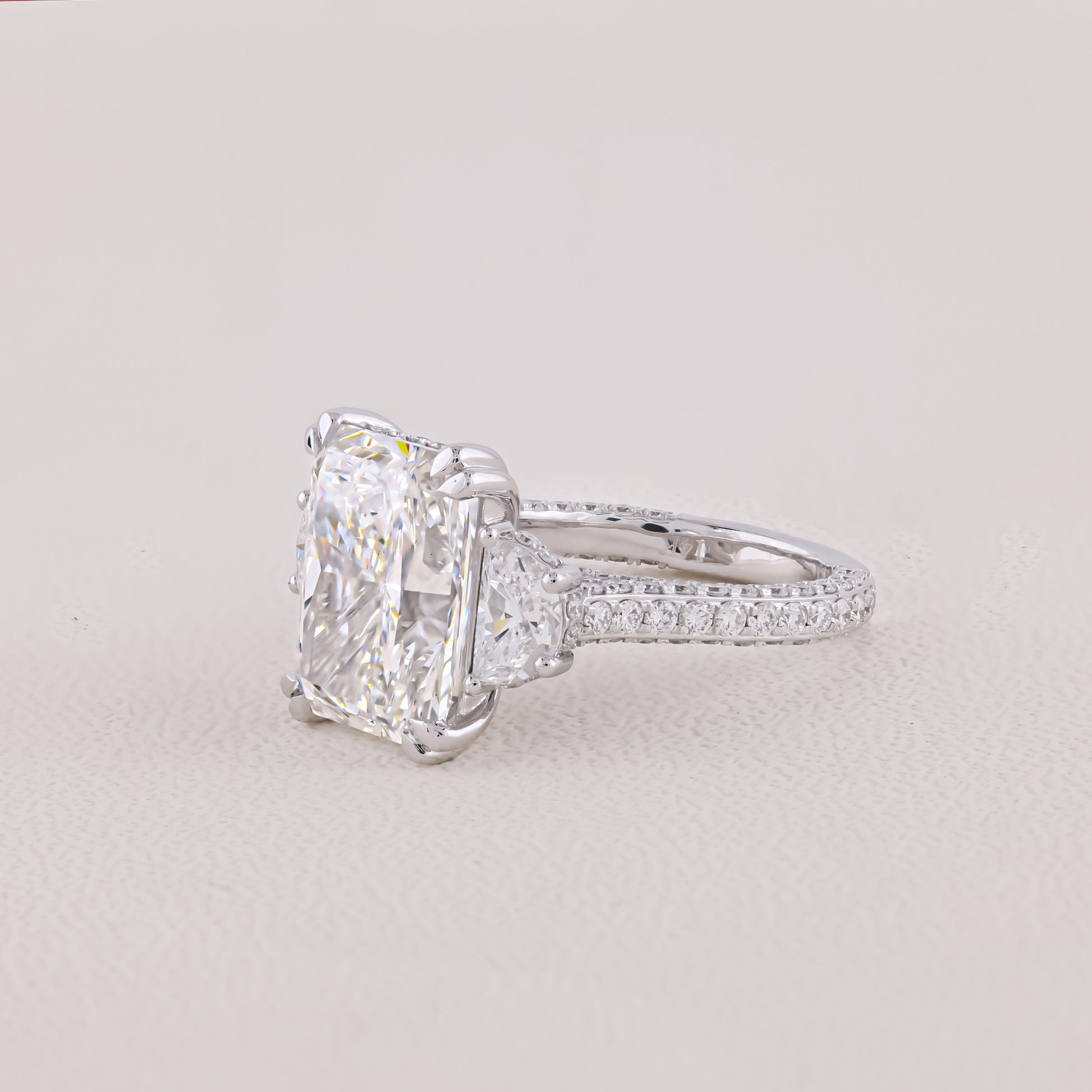 Diamond ring with a large central gemstone on a light gray background