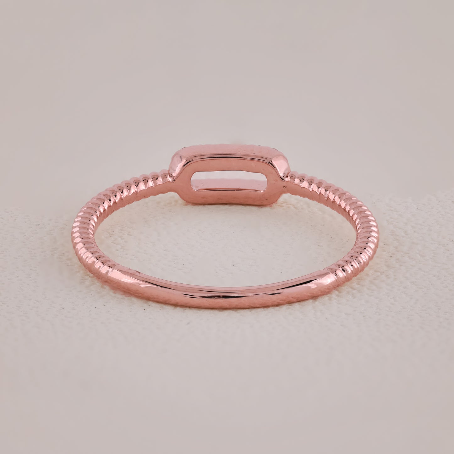 Rose gold ring on a light beige background