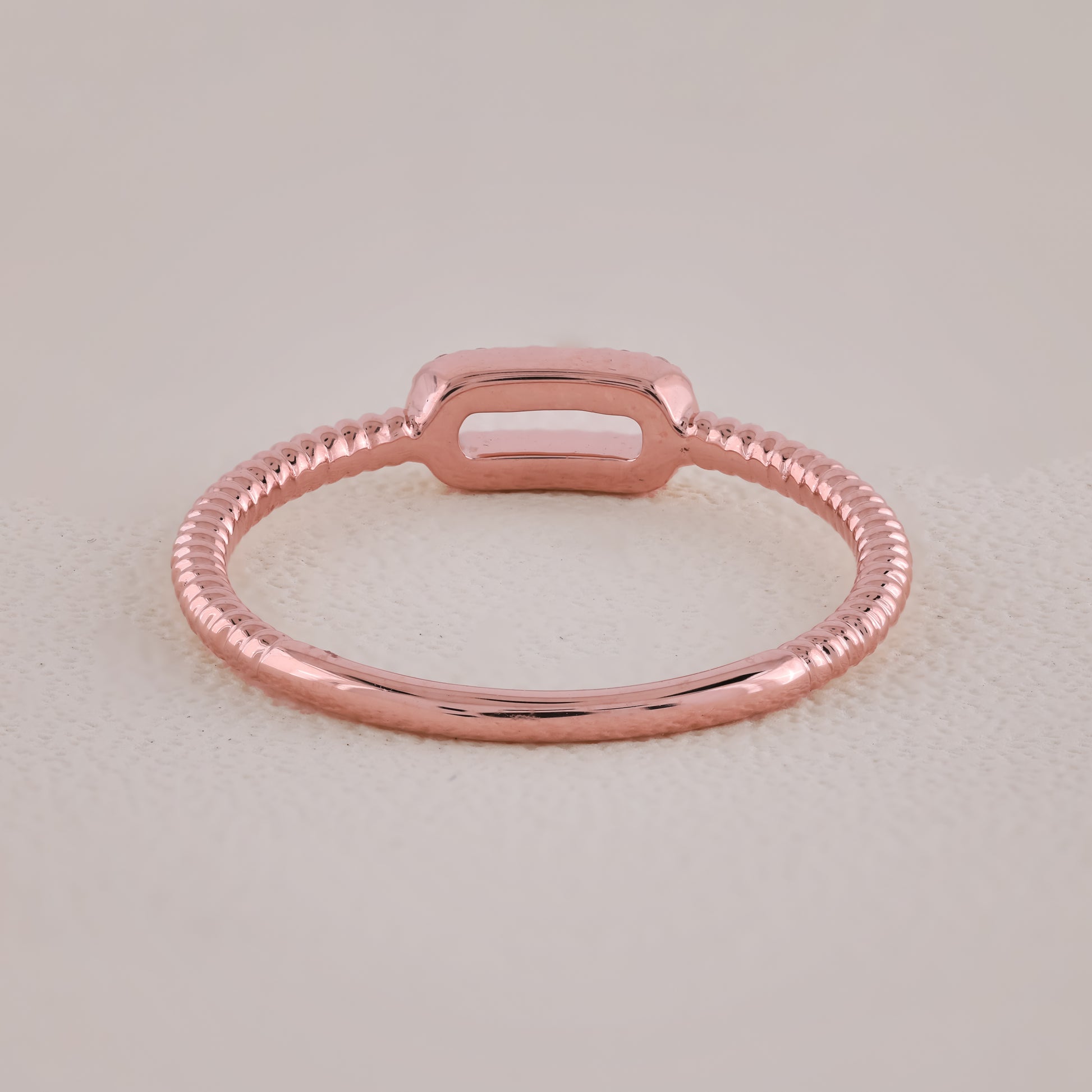 Rose gold ring on a light beige background