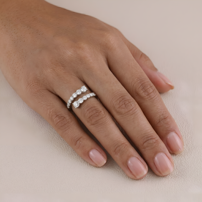 Hand wearing a silver ring with diamonds on a beige background