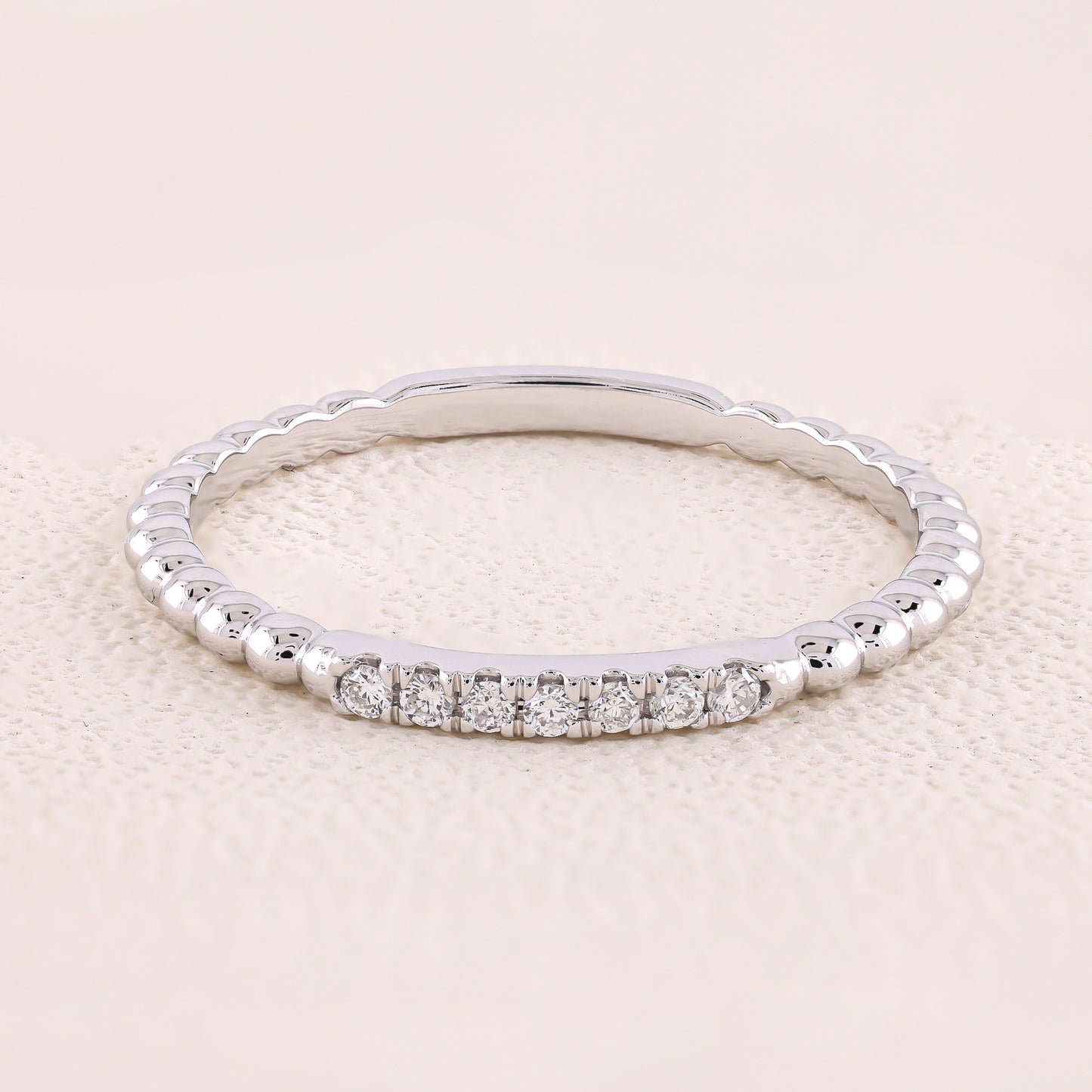 Silver ring with small diamonds on a light beige background