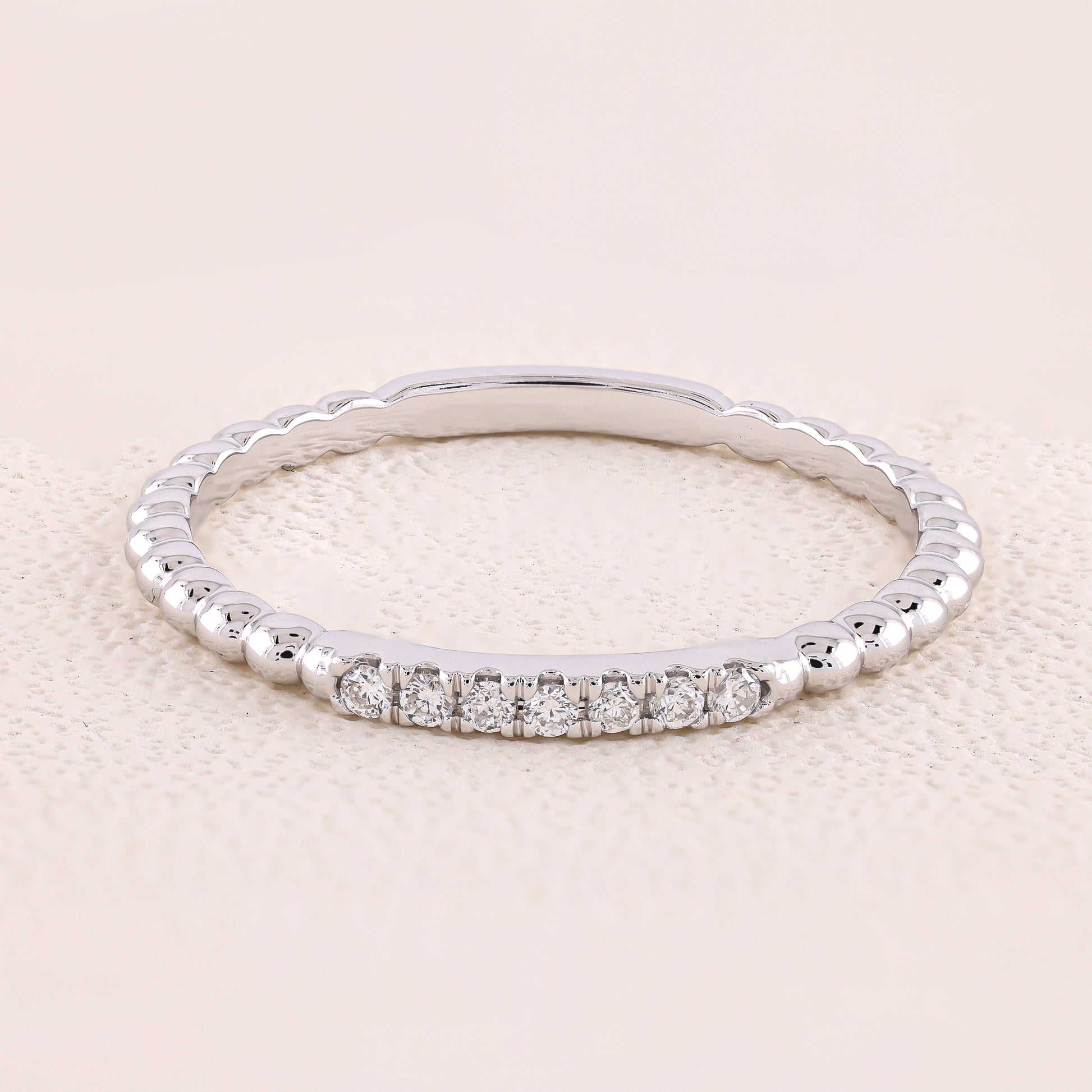 Silver ring with small diamonds on a light beige background