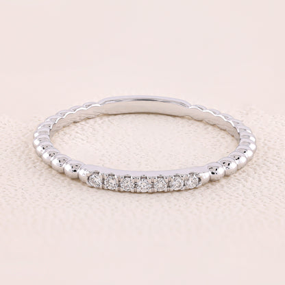 Silver ring with small diamonds on a light beige background