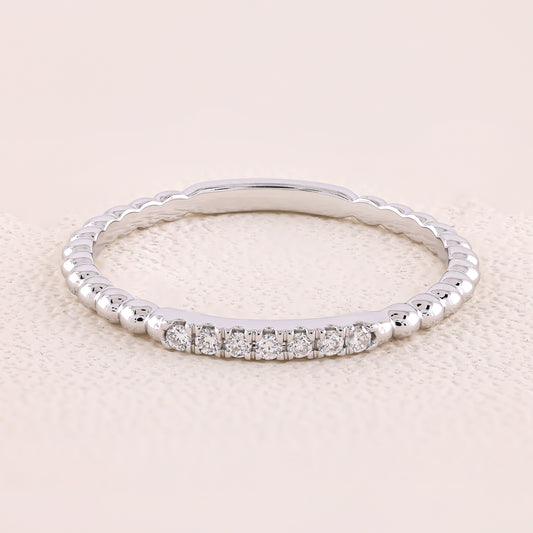 Silver ring with small diamonds on a light beige background