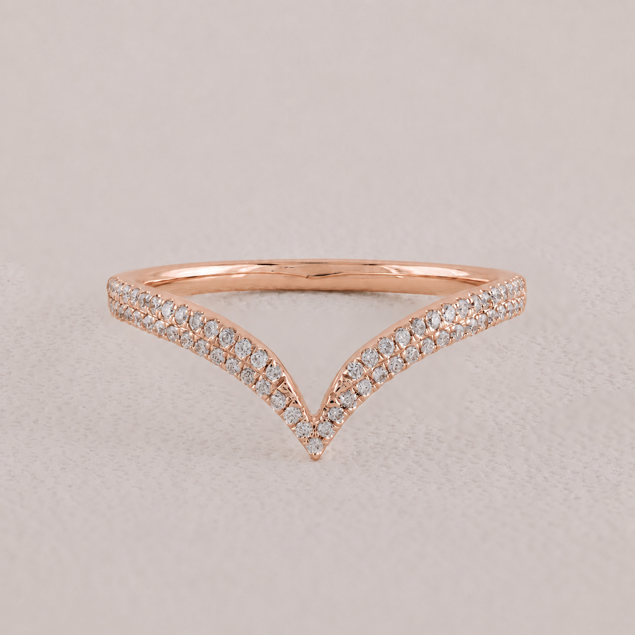 Rose gold ring with diamond accents on a light gray background
