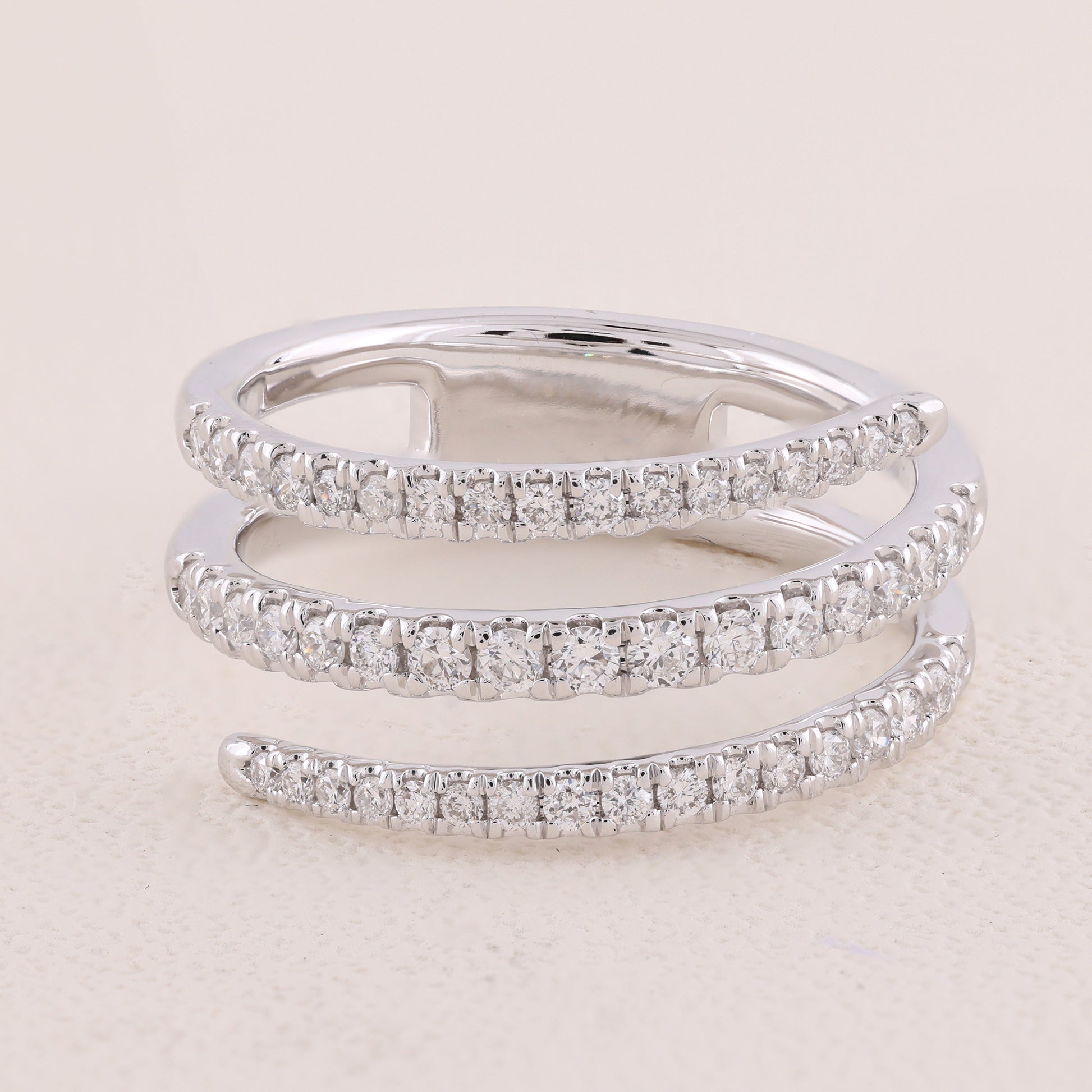 Two diamond-studded silver rings on a light beige background