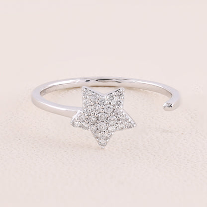 Silver ring with a star-shaped diamond design on a light pink background