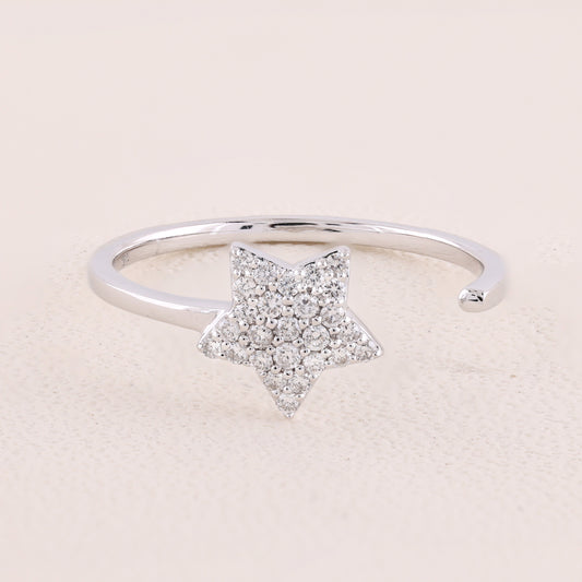 Silver ring with a star-shaped diamond design on a light pink background