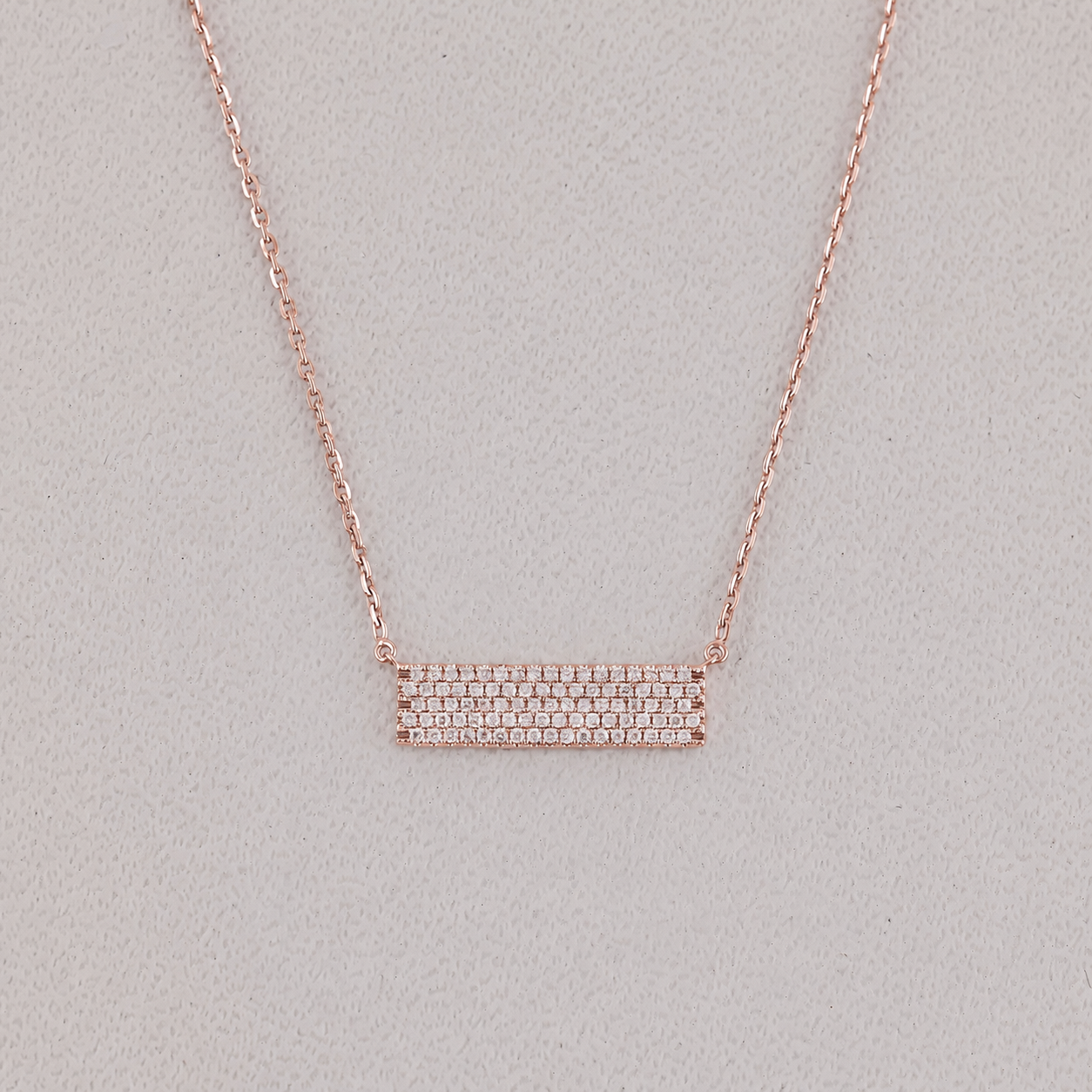 Rose gold necklace with a bar pendant on a light gray background