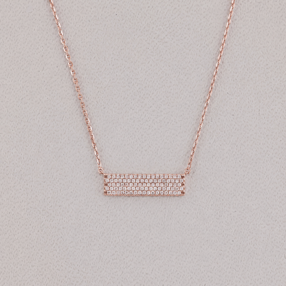 Rose gold necklace with a bar pendant on a light gray background