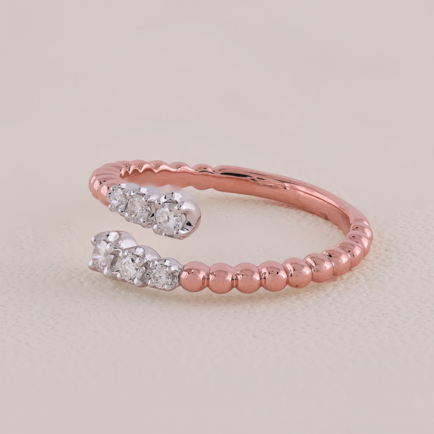 Rose gold ring with diamond accents on a light beige background