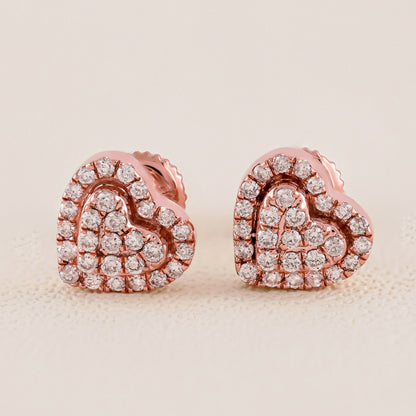Heart-shaped earrings with rose gold and clear gemstones on a beige background