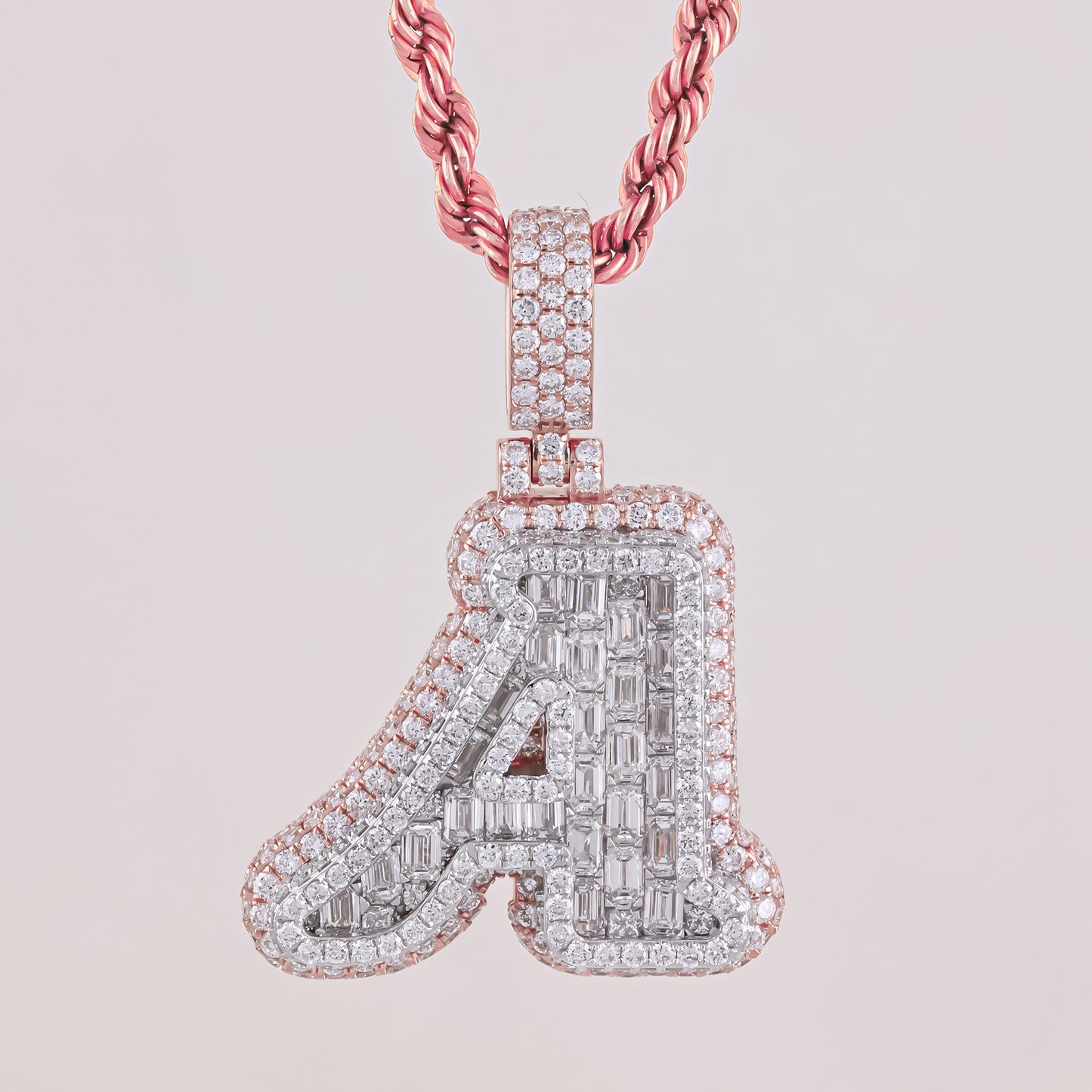 Diamond-studded letter 'A' pendant on a pink chain against a light pink background